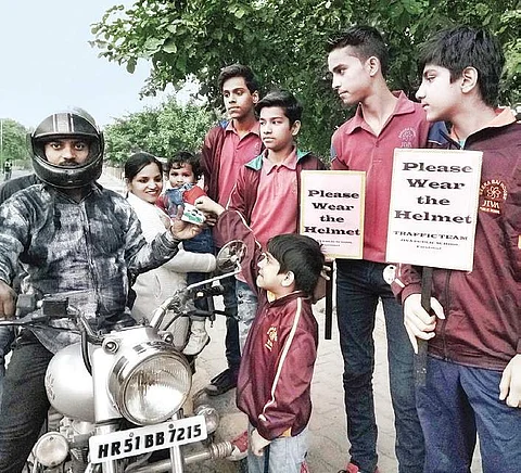 Members of the Traffic Team stand with placards near their school to urge motorists to follow traffic safety rules