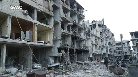 Syrians walk between destroyed buildings during airstrikes and shelling by Syrian government forces in Ghouta. (File | AP)