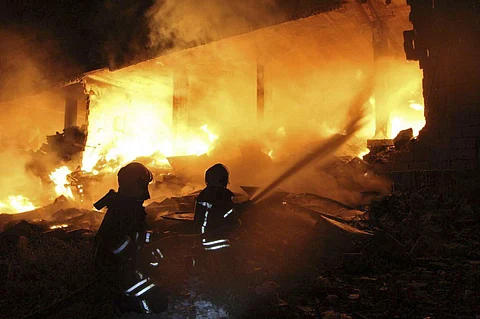 This photo provided by the Syrian Civil Defense White Helmets, which has been authenticated based on its contents and other AP reporting, shows Syrian White Helmet civil defense workers extinguishing a fire at the scene of an explosion that hit a five-sto