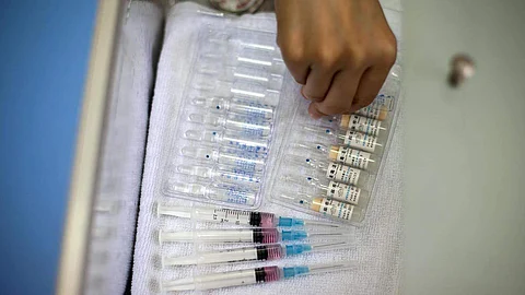 A nurse prepares vaccine shots against measles at a clinic.