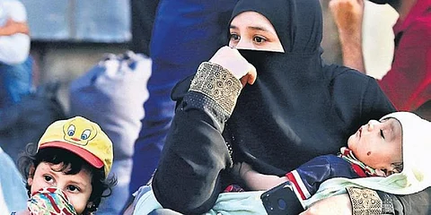 A woman with her children waits for a bus outside Dharavi slums in Mumbai. (Photo | PTI)