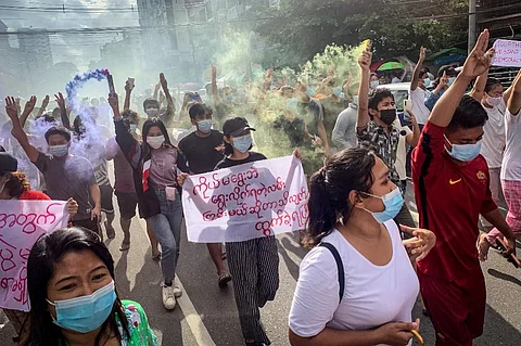 Protesters make the three-finger salute and hold flares during a demonstration against the military coup in Yangon on July 3, 2021. (Photo | AFP)