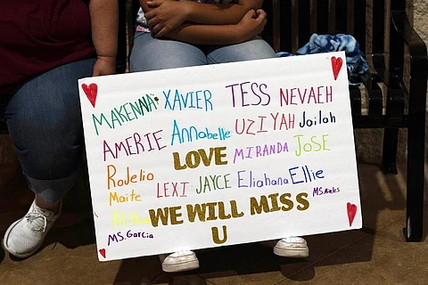 Stormy Flores, 11, sits with a sign bearing the names of the Robb Elementary School shooting victims during a prayer vigil in Uvalde, Texas. (Photo | AP)