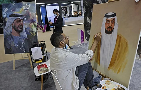 An artist draws a portrait of the late UAE president Sheikh Khalifa bin Zayed al-Nahyan (R) next to a finished portrait of his brother and current President Mohamed bin Zayed al-Nahyan (L). (AFP)