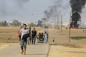 Palestinians walk away from the kibbutz of Kfar Azza, Israel, near the fence with the Gaza strip. (Photo | AP)