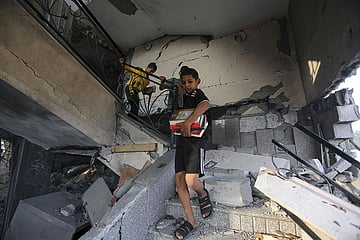 Palestinian kids take religious books out of a mosque destroyed in an Israeli air strike in Khan Younis, Gaza Strip. (Photo | AP)