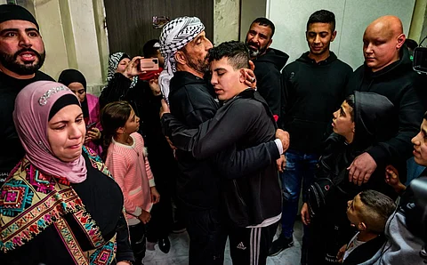 Ahmad Salaima, a 14-year-old Palestinian released under an extended truce deal, embraces his father as his mother (L) looks on at his home in Israeli-annexed east Jerusalem. (Photo | AFP)