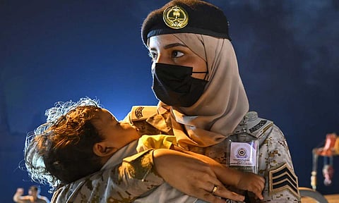 مجندة تحمل طفلا من أبناء الرعايا الذين تم إجلاؤهم