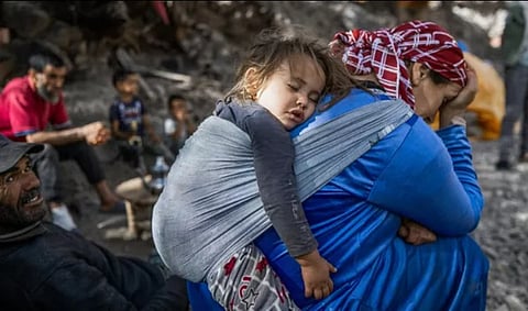سيدة مغربية طالتها تداعيات الزلزال بينما تحمل ابنتها النائمة