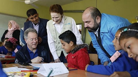 In this picture taken on March 3, 2020 and provided by UNICEF, UNICEF Executive Director Henrietta H. Fore, center, and WFP Executive Director, David Beasley, left, seated, interact with 3rd grade children, at Tal-Amara school, southern Idlib, Syria. (Omar Sanadiki/UNICEF via AP)