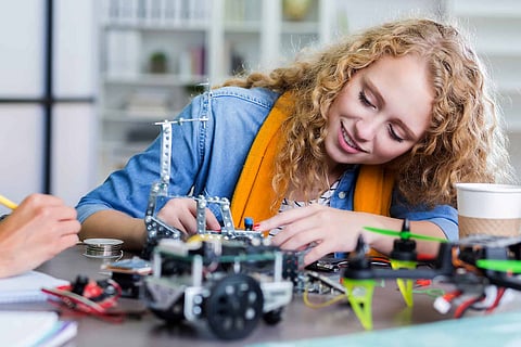 Confident high school student concentrates while building a robotic vehicle.
