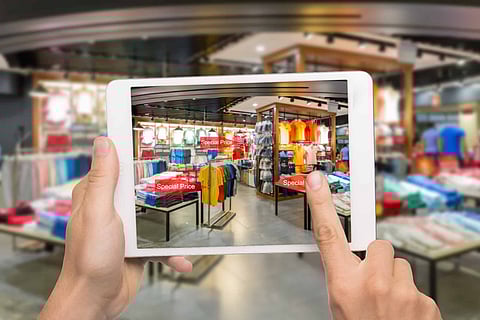 Augmented reality marketing concept. Hand holding digital tablet smart phone use AR application to check special sale price in retail fashion shop mall