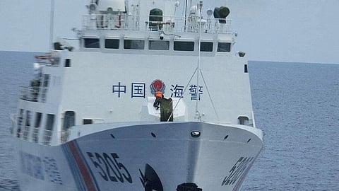 A crewmember of the China Coast Guard vessel 5205 removes the cover of a 70mm gun and aims it toward the Philippine Coast Guard patrol vessel BRP Teresa Magbanua near Second Thomas Shoal in the South China Sea, August 2022.