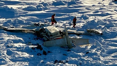 US Coast Guard personnel inspect the wreckage of a downed Cessna on sea ice on the Bering Sea