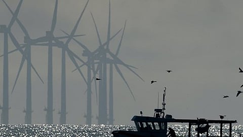 A fishing vessel with an offshore wind farm in the background