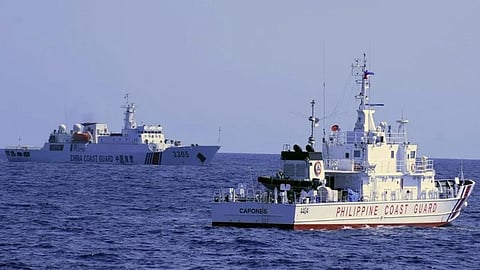 A China Coast Guard ship (background) sails near the Philippine Coast Guard multi-role response vessel BRP Capones during the latter's patrol at Scarborough Shoal, 124 nautical miles west of Zambales province in the northwestern Philippines on March 2, 2022.
