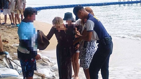 Police and bystanders assisting the female tourist after pulling her out of the water