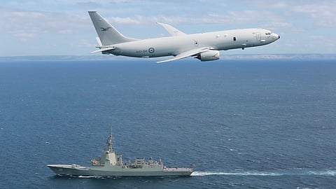 A Royal Australian Air Force P-8A Poseidon maritime patrol aircraft flies above the Royal Australian Navy air warfare destroyer HMAS Hobart.
