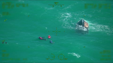A US Coast Guard rescue swimmer assists in the rescue of four survivors of a capsized vessel approximately 30 miles north of Key West, Florida, December 31, 2025.
