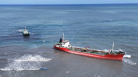 A tug manoeuvres into position prior to attaching towing lines to the grounded tanker Espada off Naujan municipality in the Philippines' Oriental Mindoro province.