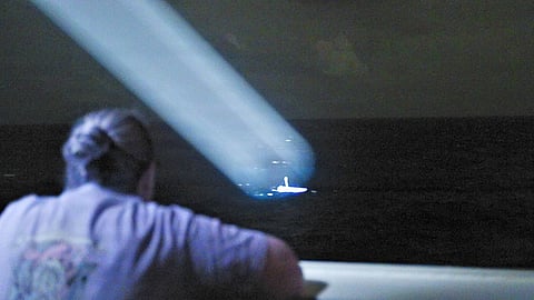 Lieutenant Commander Stephanie Jocis, operations officer aboard the national security cutter USCGC Midgett, observes a 23-foot single-outboard skiff vessel, carrying three members of a missing family in the waters of Chuuk State, Federated States of Micronesia, in Midgett’s searchlight during the early hours of April 6, 2026. The crew of Midgett rescued the family after the vessel went missing on March 30 in the waters of Chuuk State.