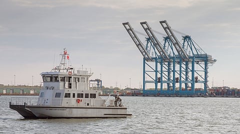 The US Army Corps of Engineers survey vessel Ewell sails past cranes at the Virginia Port Authority’s Norfolk International Terminal.