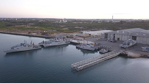 Austal's shipyard in Henderson, Western Australia. Three Evolved Cape-class patrol boats and three smaller Guardian-class patrol boats are moored pierside while a fourth Evolved Cape-class boat is mounted on a slipway.