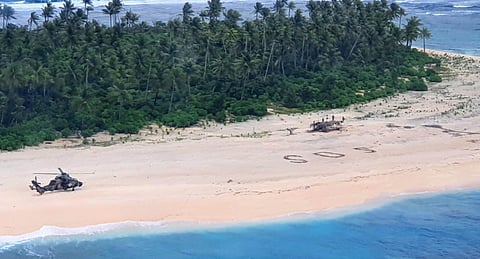 An Australian Army Tiger helicopter lands on Pikelot Island in Micronesia. The SOS message of the stricken sailors can be seen on the beach. (Photo: Australian Defence Force)