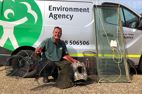 An Environment Agency fisheries enforcement officer with some confiscated illegal traps (Photo: UK Environment Agency)
