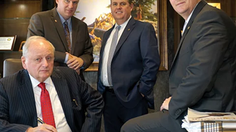 All of the Nesses worked at other banks before joining First Dakota. Chairman and CEO Larry (seated in chair) worked at banks in Mitchell and Volga, in addition to working as an OCC examiner; President and Chief Operating Officer Rob (standing, left), like his father, worked at the OCC; Sioux Falls Market President Michael worked at a bank in Lincoln, Neb, and Executive Vice President Aaron (seated on desk) worked at a bank in Texas.