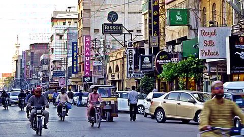 Photo of street in Karachi with shops, motorbikes and cars