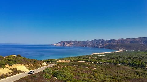 Photo of panoramic view of the Sardinian coastline with clear blue waters and lush greenery