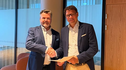 The source image shows two company representatives with documents in connection with Byhmgard's binding agreements to acquire the rights to Hitura, a 50 MW standalone BESS project being developed in Finland.