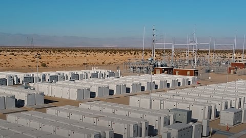 Aerial view of white battery enclosure rows and a substation on arid ground in Texas.