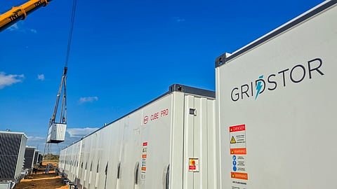 White BYD battery containers with GridStor branding, as a crane lifts a unit into place.
