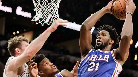 Philadelphia 76ers’ Joel Embiid (21) shoots as 76ers’ Jimmy Butler, center, and San Antonio Spurs’ Jakob Poeltl look on during the first half of an NBA basketball game, Monday, Dec. 17, 2018, in San Antonio. (AP Photo/Darren Abate) 