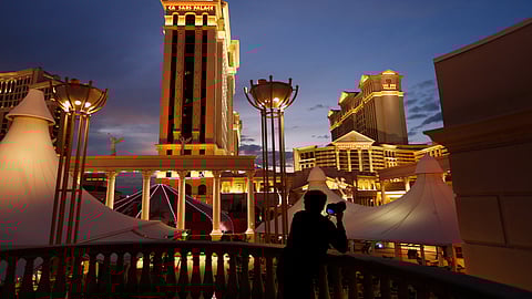 FILE - In this Monday, Jan. 12, 2015, file photo, a man takes pictures of Caesars Palace hotel and casino, in Las Vegas. The NFL is partnering with Caesars Entertainment as its first official casino sponsor, but the deal does not include sports betting or fantasy football. The multiyear arrangement announced Thursday, Jan. 3, 2019, begins with this weekend’s playoffs. (AP Photo/John Locher, File)