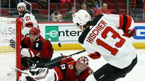 New Jersey Devils center Nico Hischier (13) scores a goal as he gets the puck past Arizona Coyotes goaltender Darcy Kuemper (35) and center Clayton Keller (9) as Devils right wing Kyle Palmieri (21) watches during the first period of an NHL hockey game Friday, Jan. 4, 2019, in Glendale, Ariz. The puck did not actually go into the net but it was ruled a goal due to Coyotes center Clayton Keller moving the net out of place and the puck would have gone in for the score. (AP Photo/Ross D. Franklin)