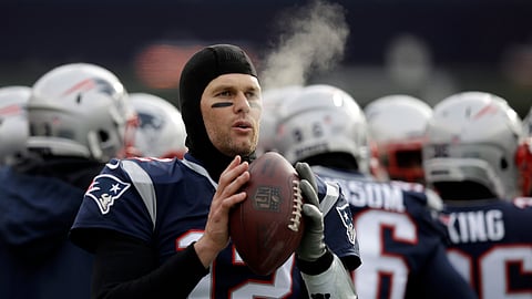 FILE - In this Dec. 31, 2017, file photo, New England Patriots quarterback Tom Brady keeps limber on the sideline in the cold weather during the first half of an NFL football game against the New York Jets, in Foxborough, Mass. His coach downplays it, but Tom Brady knows the cold-weather New England Patriots should have an advantage when they host the warm-weather Los Angeles Chargers in Sunday’s AFC Divisional Round game. (AP Photo/Charles Krupa, File)