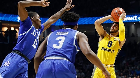 Marquette’s Markus Howard (0) shoots against Xavier’s Naji Marshall (13) and Quentin Goodin (3) in the second half of an NCAA college basketball game, Saturday, Jan. 26, 2019, in Cincinnati. (AP Photo/John Minchillo)