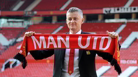 Manchester United soccer team manager Ole Gunnar Solskaer holds a team scarf.