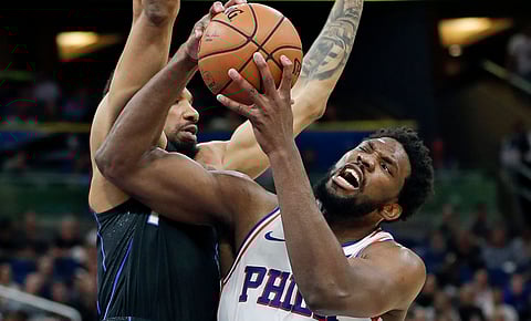 Philadelphia’s Embiid struggles to get his shot up against Orlando’s Khem Birch Monday (John Raoux)