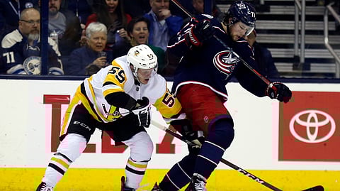 Pittsburgh Penguins forward Jake Guentzel reaches for the puck against Columbus Blue Jackets forward Josh Anderson during an NHL hockey game on March 9, 2019. (Paul Vernon)