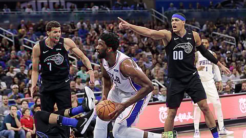 Philadelphia 76ers’ Joel Embiid, center, is called for a charge as he runs into Orlando Magic’s Khem Birch, lower left, as Magic’s Michael Carter-Williams (7) and Aaron Gordon (00) look on during a game on March 25, 2019