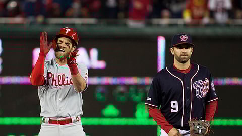 Phillie Bryce Harper, left, celebrates his RBI hit while on second base with Nationals second baseman Brian Dozier, Tuesday, April 2, 2019. (AP Photo/Alex Brandon)