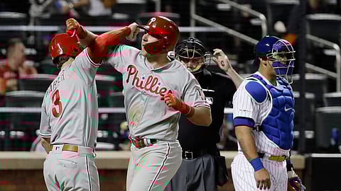 Mets catcher Wilson Ramos looks away as Phillies’ Bryce Harper, left, celebrates with Rhys Hoskins, center, after Hoskins hit a two-run home run in the ninth inning, Wednesday. (AP Photo/Frank Franklin II)