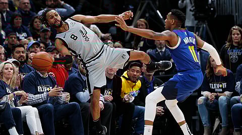 San Antonio Spurs guard Patty Mills, left, reaches out to save a ball from going out of bounds as Denver Nuggets guard Monte Morris defends in the second half of Game 1 of an NBA first-round basketball playoff series, Saturday, April 13, 2019, in Denver. The Spurs won 101-96. (AP Photo/David Zalubowski)