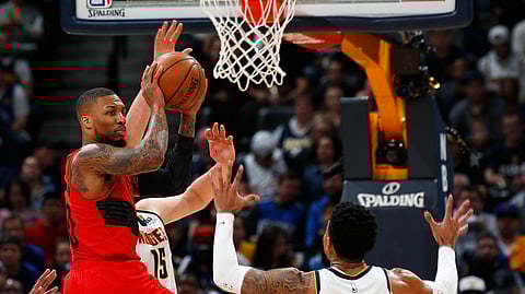Portland Trail Blazers guard Damian Lillard, center, drives to the rim against Denverin the NBA Playoffs.