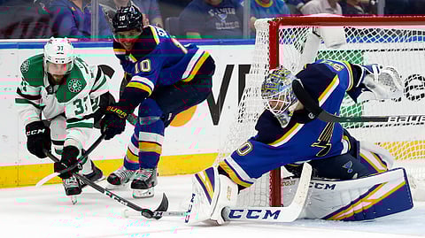 Blues goaltender Joordan Binnington pokes the puck away from Stars center Justin Dowling as Brayden Schenn defends in Game 7 on May 7 (Jeff Roberson)