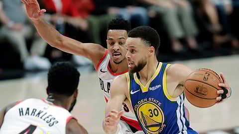 Golden State Warriors guard Stephen Curry drives past Portland Trail Blazers guard CJ McCollum, center, during the first half of Game 3 of the NBA basketball playoffs Western Conference finals on May 18, 2019.